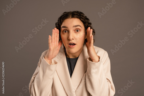 Fotografía Stunned woman looking at camera with wide eyes holding hands near cheeks in fear
