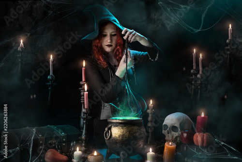 Konstfotografi Witch with magic wand casts spell, witch's cauldron, boiling magic potion, room with candles, skull