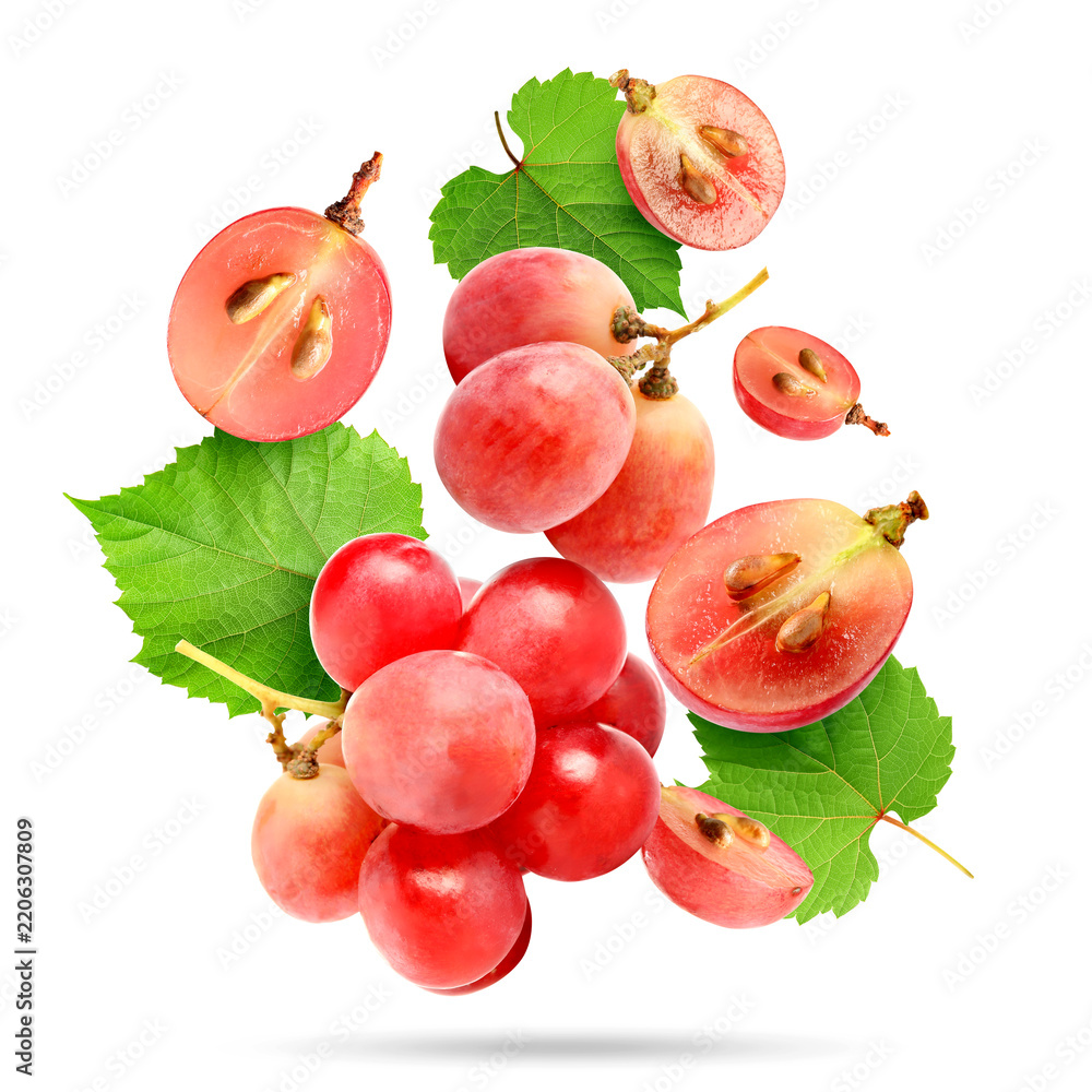 Obraz premium Fresh pink grapes and green leaves falling against white background