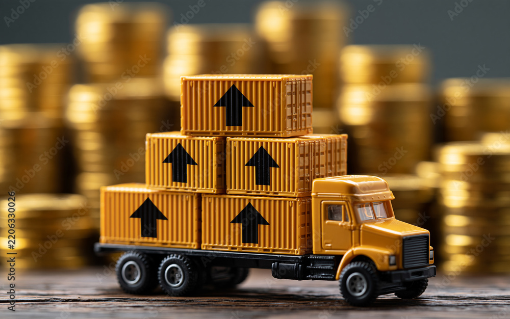 Obraz premium Yellow cargo containers with black up arrows stacked on miniature semi truck. Gold coin stacks form background. Concept of import tariff increase, rising trade costs, growing logistics expenses