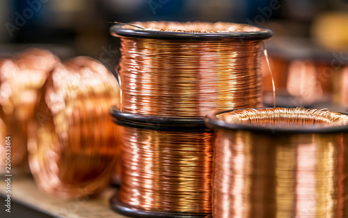 Copper wire coils ready for electronics assembly and manufacturing. Shiny metal material, fine gauge wire spools for precise component building. Industrial workshop setup