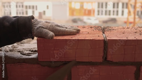 Mason carefully placing bricks securely. Urban construction professional meticulously arranging bricks with trowel amidst safety precautions and detailed craftsmanship