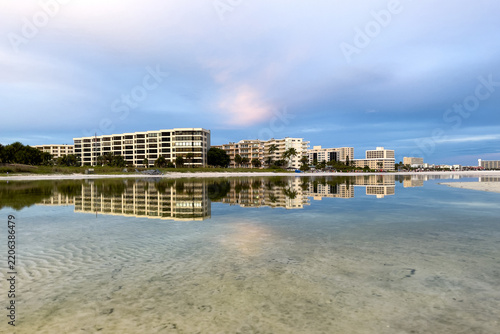 Fotografie Beachfront condominiums reflect perfectly in calm tide pool waters on Siesta Key Beach, Florida, at dusk, showcasing a tranquil, mirror-like aesthetic and soft evening light