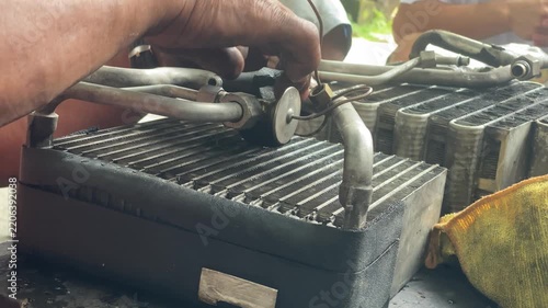 technician is assembling pieces of a broken car air conditioning evaporator on the pavement.