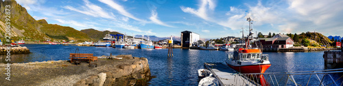 Panorama of Ballstad shipyard with machine workshop, fishing boats and harbor against the Lofoten mountain landscape.