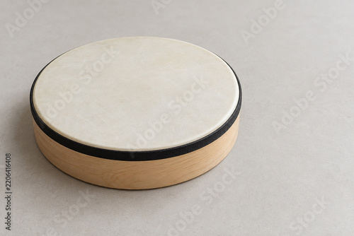 Wooden frame drum with a plain cream drumhead on a light surface