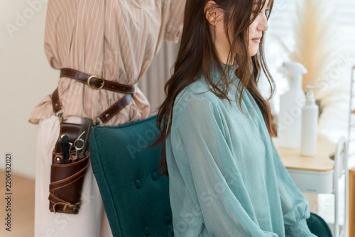 Long-Haired Woman Receiving a Hair Treatment from a Hairstylist Wearing a Scissor Holster at a Hair Salon