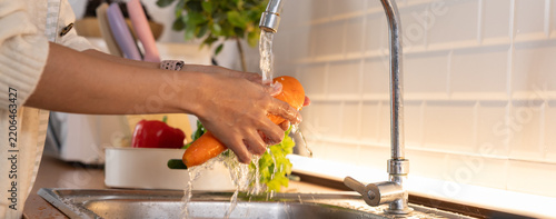 Person washing fresh vegetable under running water in bright kitchen sink, supporting healthy food preparation and daily household hygiene with natural light and clean surroundings