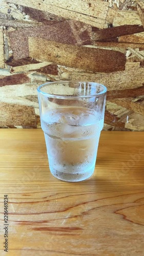 木目のテーブルに置かれた水滴のついた冷たい水のグラス