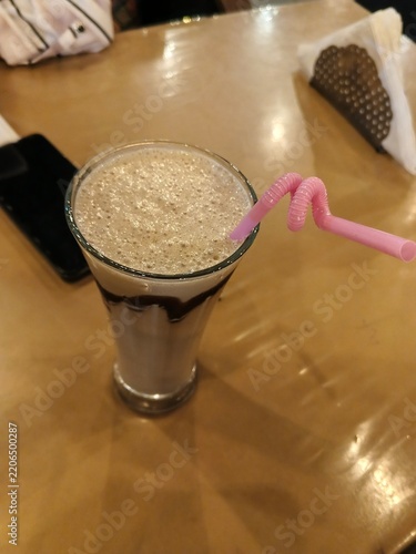 creamy iced coffee in a tall glass with pink straw