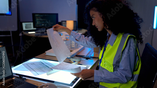Female engineer reviewing architectural blueprints and construction planning documents