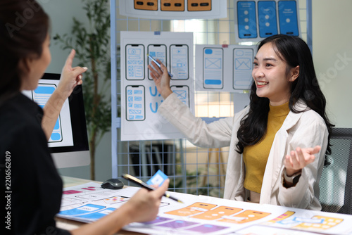 Asian woman creating user experience interface designs, discussing web application layouts and developing prototypes for digital products.