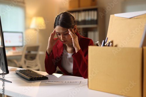 Stressed young woman planning resignation at night office.