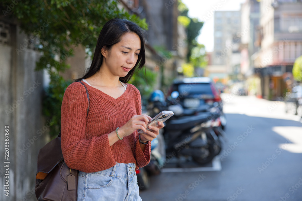 Obraz premium Woman typing on phone on street at Taipei city