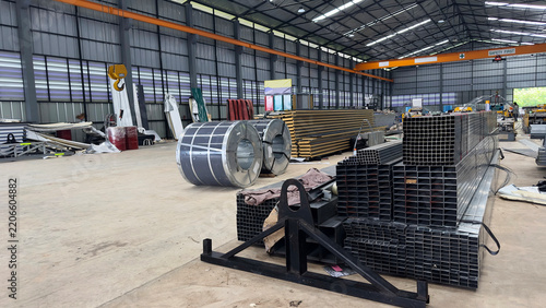 Steel coils and metal pipes stored inside an industrial warehouse factory.