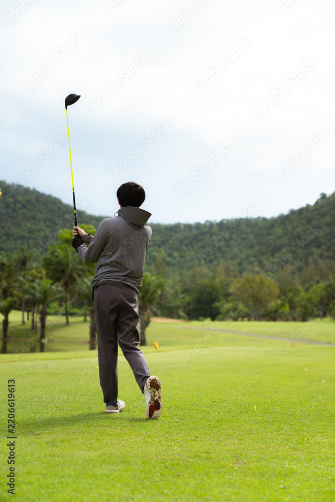 Fototapeta premium Golfer completing swing follow through with driver on green course