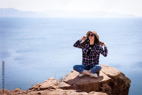 Woman Sitting on Rock Overlooking Sea at Cliff Edge
