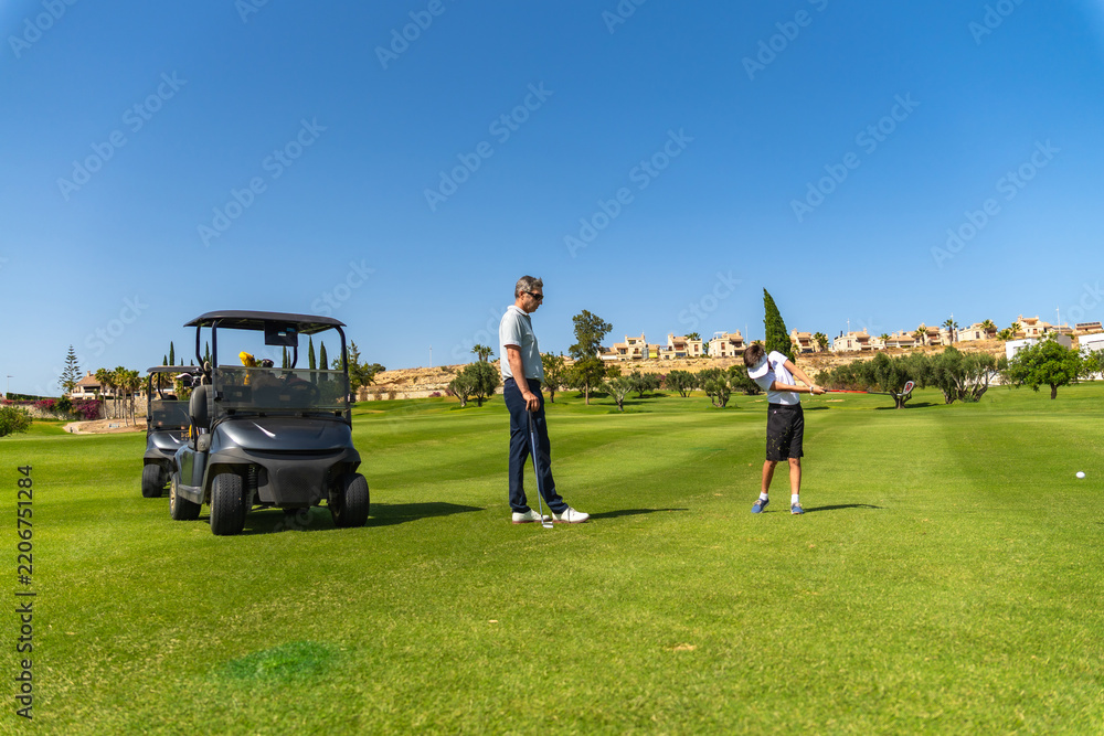 Obraz premium Instructor teaching young man proper golf swing on course