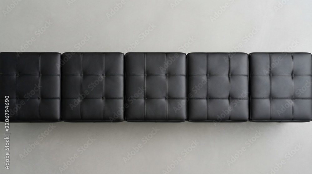 Naklejka premium Top View of Five Black Tufted Synthetic Leather Ottoman Stools Arranged in a Line on a Gray Floor for Modern Interior Design