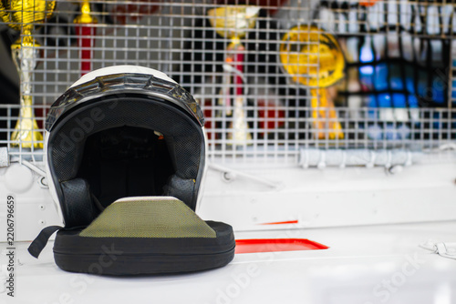 Canvas Print Black hockey helmet resting on white rink boards with trophies and sports equipm