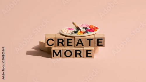 Wooden blocks spelling create more with an artist palette and brush on top.