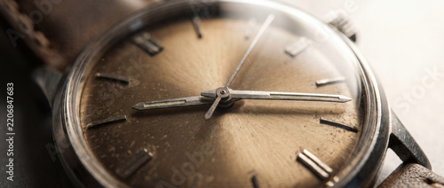 A close-up shot of a vintage wristwatch, showing its textured metal dial, metallic hands, and leather strap, focusing on timekeeping details.