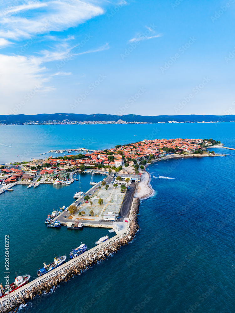 Fototapeta premium Coastal view of a harbor with boats and a distant town under a blue sky
