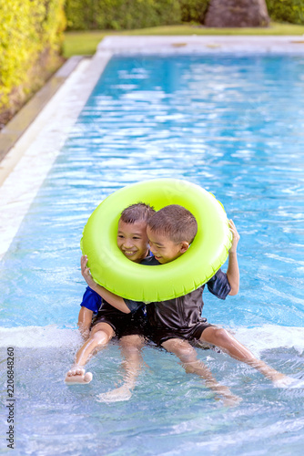 Two Brothers Sharing a Swim Ring Together in the Pool on Vacation
