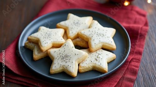 Star shaped sugar cookies with white icing and silver sprinkles on a dark grey plate