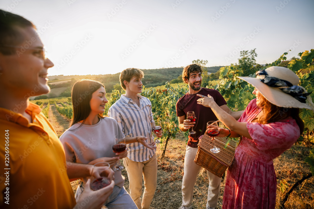 Obraz premium Young friends conversing and laughing together at vineyard wine tasting