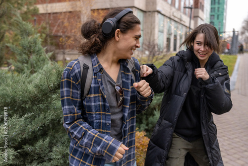 Young man and woman laughing and playing around, pretending to fight in a park during autumn.
