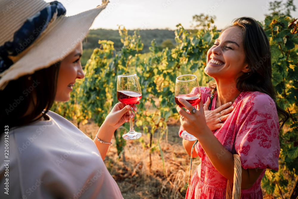Obraz premium Two female friends sharing a heartfelt laugh while holding wine glasses