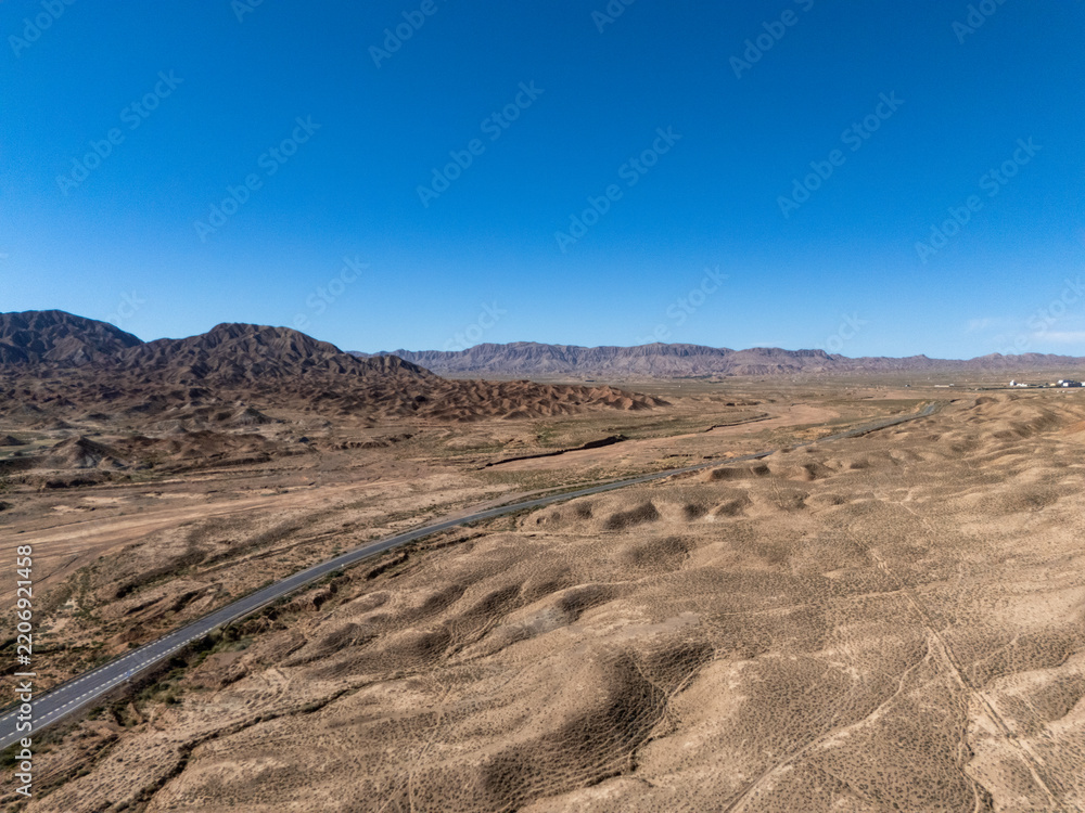 Naklejka premium winding road traversing arid desert mountains under blue sky