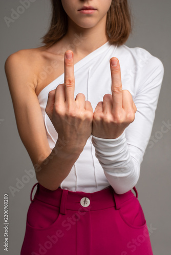 Фотография teen girl showing middle finger gesture with both hands expressing aggression an