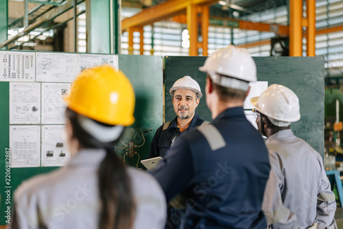 Professional senior lead supervisor engineer man training young engineers team in industry factory