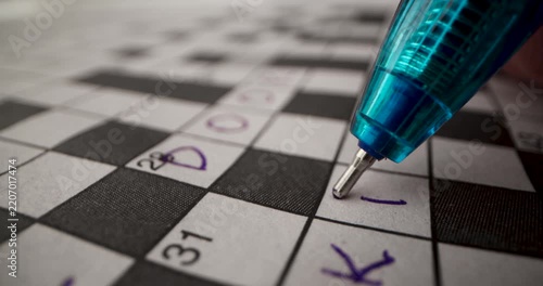 Brain training games. Hand writing answer in crossword puzzle. closeup