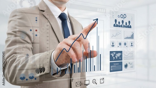 Businessman using a futuristic digital interface to analyze business growth charts and financial data