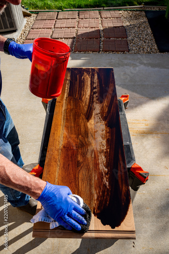 Home woodworker applies stain to a piece of wood
