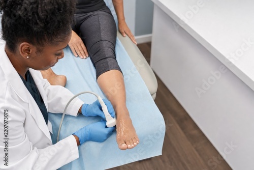Podiatrist examining patient's foot with ultrasound