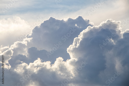 Majestic cumulus clouds illuminated by sun in blue sky