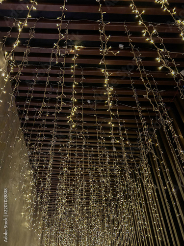Hundreds of delicate warm LED fairy lights cascading vertically from a dark wooden slatted ceiling.