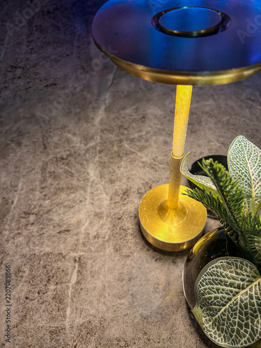a contemporary brass cordless LED table lamp casting a warm downlight across a textured grey marble tabletop.