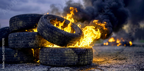Burning stack of tires creating large black smoke and flames on roadway