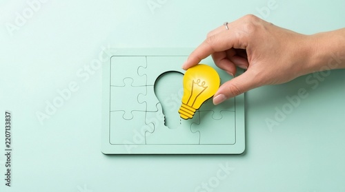 Hand placing a yellow lightbulb puzzle piece to complete a puzzle, symbolizing a creative solution and innovative idea