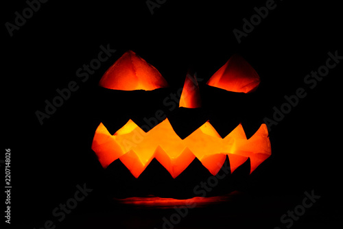 Carved halloween pumpkin jack-o-lantern glows in a darkness
