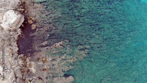 Aerial view of rocky coastline meeting clear blue water