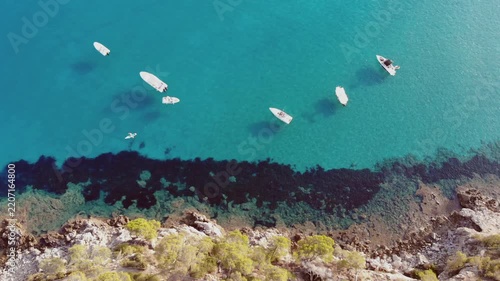 Aerial view of boats on turquoise water near rocky shore