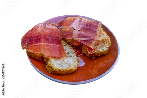 Iberian ham slices serving on bread as a spanish tapa appetizer