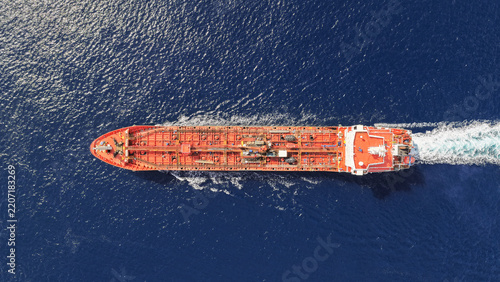 Aerial drone top down photo of small oil - chemical tanker cruising in deep blue open ocean sea