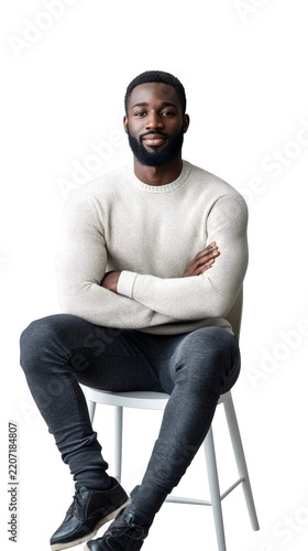 Confident young african american man sitting on a white chair with arms crossed